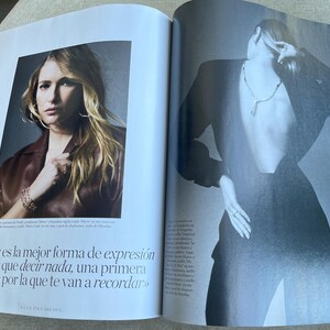 Puede incluir: Una revista de moda con dos im&aacute;genes. Una muestra a una mujer rubia con una blusa burdeos y joyas. La otra muestra a una persona con un traje negro y un collar. El texto en espa&ntilde;ol dice: &laquo;La moda es la mejor forma de expresi&oacute;n sin tener que decir nada, una primera impresi&oacute;n por la que te van a recordar&raquo;.