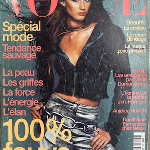 May include: A vintage Vogue Paris magazine cover from August featuring a person with long dark hair wearing a black jacket and metallic silver pants with a large silver chain belt. The cover includes bold text in red, white, and yellow.