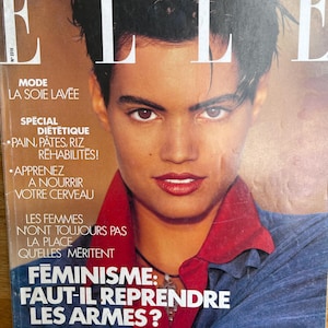 May include: Cover of Elle magazine featuring a woman with dark hair and red lipstick. The cover includes the magazine's title, issue number, and French text about fashion, diet, and feminism. The cover's theme is feminism.