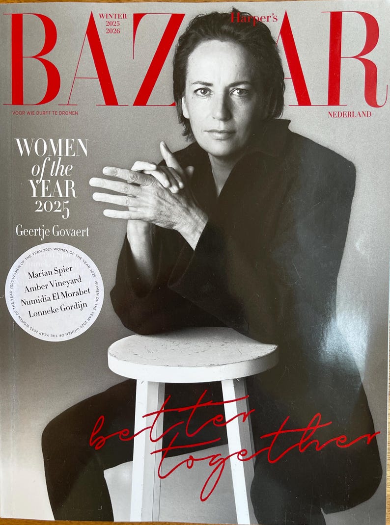 May include: A magazine cover featuring a woman in a black outfit, seated on a white stool. The magazine title "BAZAR" is in large red letters. Text includes "WOMEN of the YEAR 2025" and "Geertje Govaert". The words "Better Together" are written in red.