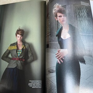 May include: Fashion editorial spread featuring a woman in a gray blazer with a yellow stripe, a plaid top, and a burgundy belt. The model is also wearing a long, dark skirt. The second image shows the model in a dark, textured dress.