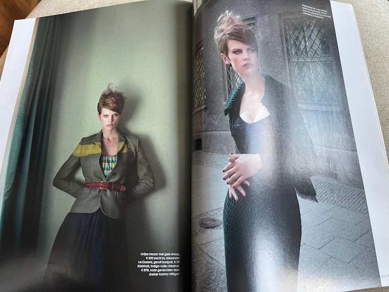 May include: Fashion editorial spread featuring a woman in a gray blazer with a yellow stripe, a plaid top, and a burgundy belt. The model is also wearing a long, dark skirt. The second image shows the model in a dark, textured dress.