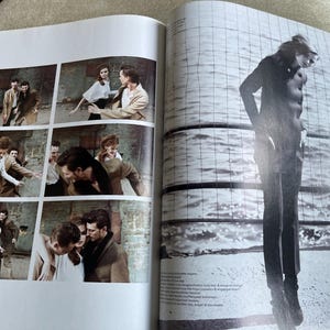 May include: A magazine spread featuring a fashion editorial. The left page shows a series of six small images of a couple interacting with other people. The right page features a full-length silhouette of a person standing near water.