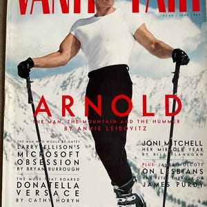 Könnte beinhalten: Titelbild des Magazins Vanity Fair mit Arnold Schwarzenegger in weißem T-Shirt und schwarzer Hose, mit Skistöcken. Der Titel "VANITY FAIR" und der Name "ARNOLD" sind rot. Ausgabe Juni 1997.