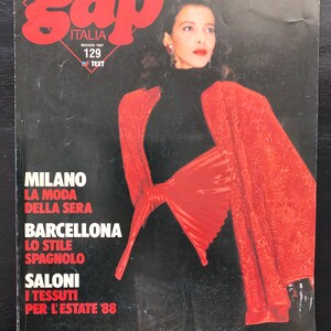 Pode incluir: Uma capa de revista com uma mulher vestindo uma jaqueta vermelha com um grande laço. A revista é intitulada "gap" e o texto "ITALIA" é impresso abaixo do título. A capa também inclui o texto "MILANO", "LA MODA DELLA SERA", "BARCELLONA", "LO STILE SPAGNOLO", "SALONI", "I TESSUTI PER L'ESTATE '88".