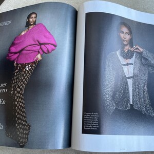 Puede incluir: Una revista de moda con una modelo con un su&eacute;ter magenta vibrante con mangas voluminosas y pantalones estampados. El texto de la p&aacute;gina izquierda dice: &laquo;Es dif&iacute;cil ser valiente, pero es una obligaci&oacute;n.&raquo;