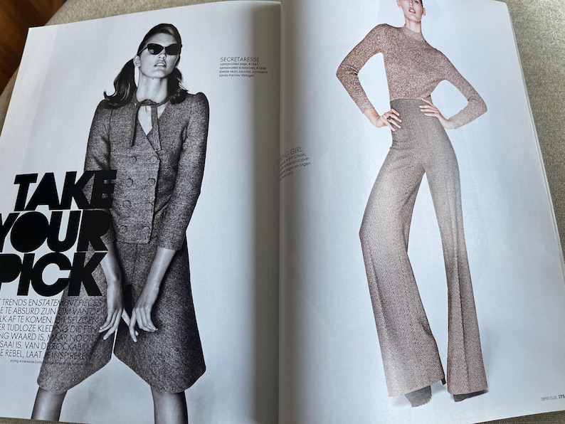 May include: A fashion magazine spread featuring two models. One model wears a gray tweed suit with a double-breasted jacket and sunglasses. The other model is in a matching knit top and wide-leg pants. The text "TAKE YOUR PICK" is visible.