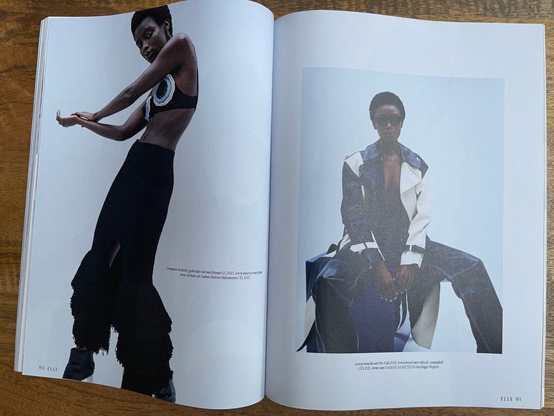 Puede incluir: Dos modelos de moda posan en un editorial de revista. La modelo de la izquierda lleva una falda negra con un dobladillo con volantes y un top negro y azul. La modelo de la derecha lleva una chaqueta blanca y azul con un top negro y unos vaqueros azules.