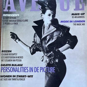 以下が含まれることがあります： 黒と白の雑誌の表紙で、黒い革のジャケットとスカートを着た女性が写っています。雑誌のタイトルは「アベニュー」で、テキストには「インタビュー」、「メイクアップ」、「ロンドンモード」、「旅行」、「無料の付録」、「写真の中の個性」、「白黒で住む」などが含まれています。
