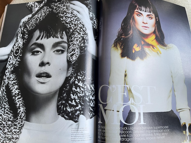 May include: A black and white fashion magazine spread featuring a woman with dark hair and makeup. The left page shows a close-up of the woman with a knitted head covering. The right page features the woman in a cream-colored top and black skirt, with the text "C'EST MOI".