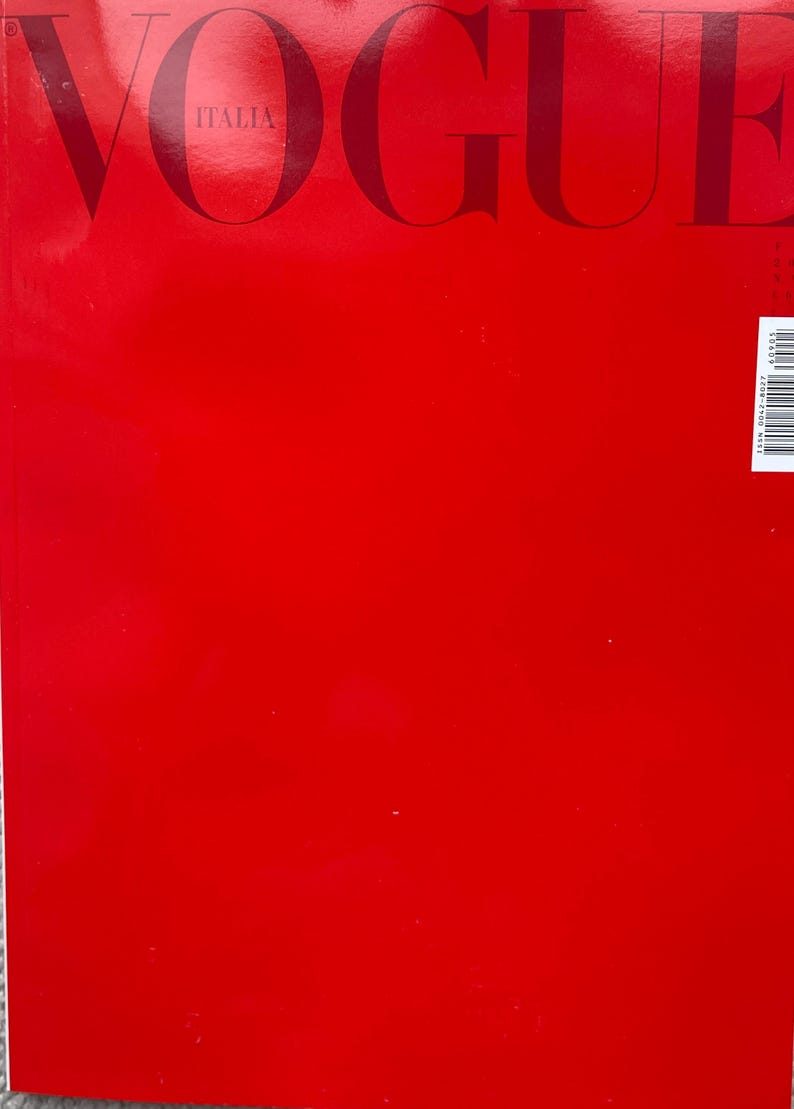 Puede incluir: Una portada de revista roja con la palabra "VOGUE" en letras grandes y oscuras en la parte superior. La palabra "ITALIA" est&aacute; debajo. El fondo es rojo liso.