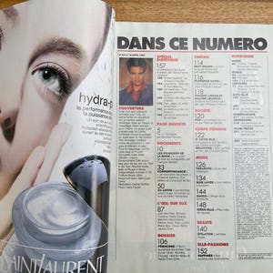 May include: Magazine spread featuring a close-up of a woman's face with blue eyes, promoting Yves Saint Laurent skincare. The text "hydra-p" and "Yves Saint Laurent" are visible. The magazine's title is "DANS CE NUMERO".
