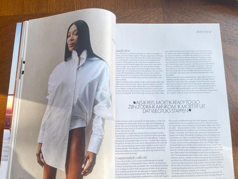May include: A magazine photograph showing a woman in a white shirt. The shirt is large and asymmetrical. The magazine pages include text and the word "Interview".