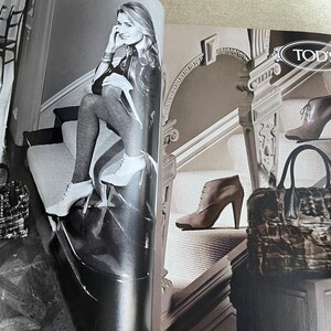May include: Black and white fashion magazine spread featuring a woman in high heels and a handbag. The magazine also displays a handbag and ankle boots. The Tod's logo is visible.