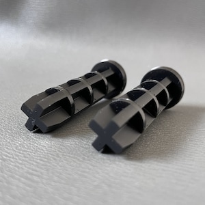 May include: Two black plastic vent plugs with a cross-shaped design at the end. The plugs have a series of holes running down the length of the plug.