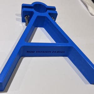 May include: A blue plastic stand with a round opening at the top. The stand is shaped like a triangle with two legs. The stand has the text "ROD VERSION 24.0mm" printed on it.