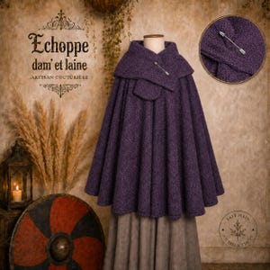Peut inclure: Une cape en laine texturée violet foncé dotée d'un large col replié fixé par une broche argentée en forme de flèche. Le vêtement présente une silhouette évasée et plissée, porté sur une jupe de couleur neutre. Le tissu a un tissage visible.