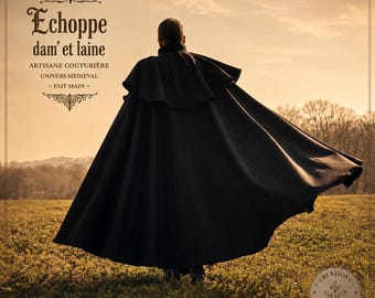 May include: A long, black, floor-length cloak with a shoulder capelet. The text on the image reads: Echoppe dam' et laine, ARTISANE COUTURIÈRE, UNIVERS MÉDIÉVAL, FAIT MAIN, and CRÉATIONS INSPIRÉES D'AUTREFOIS. The garment is shown from the back.