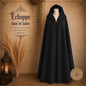 May include: A floor-length black hooded cloak featuring a structured hood and a metallic clasp at the neckline. The garment is displayed on a mannequin and includes the text "Échoppe dam' et laine ARTISANE COUTURIÈRE UNIVERS MÉDIÉVAL - FAIT MAIN".
