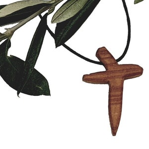 Può includere: Un ciondolo a forma di croce in legno su un cordino nero con un ramo di ulivo appeso.