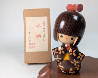Kokeshi japonés hecho a mano en kimono con cinta roja por Tomio Ishida (Fuku-F010)