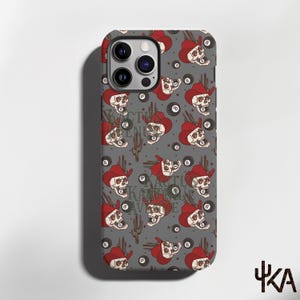 May include: A gray phone case featuring a repeating pattern of skulls wearing red cowboy hats, black eight balls, and brown cacti. The text KACTUS KAVENUE is printed in a subtle font across the center of the design, with a camera cutout at the top.