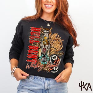 May include: Black sweatshirt with a graphic design featuring a whiskey bottle, a pool ball, and the words "Rebel Born Whiskey Bound" in red and white. The design includes floral and leopard print elements.