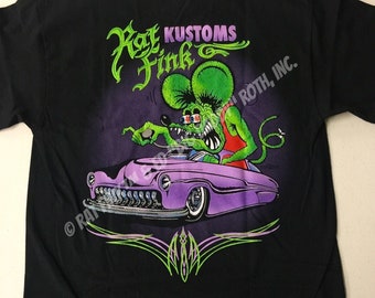 Può includere: Maglietta nera con un'auto viola e un mostro verde che la guida. Il mostro indossa una camicia rossa e ha un mohawk verde. Il testo "Rat Fink Kustoms" è sopra l'auto. Il testo "Roth, Inc." è sul lato destro dell'auto. Il testo "BACK" è in fondo alla maglietta.