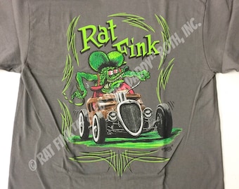 May include: Gray t-shirt with a green and brown illustration of Rat Fink driving a hot rod. The illustration is surrounded by green flames and the text "Rat Fink" and "Copyright 1960, INC."