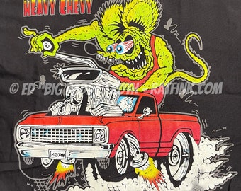 May include: A black t-shirt with a cartoon illustration of a green monster driving a red pickup truck with the words "Heavy Chevy" printed on the shirt. The monster is holding a pool cue with a billiard ball on the end. The truck has flames coming out of the exhaust pipes. The words "BACK" and "ED "BIG" DAD" are printed on the shirt.