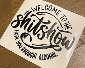 May include: White vinyl sticker with black lettering that reads "Welcome to the shitshow. Hope you brought alcohol."
