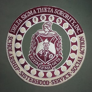 May include: A circular embroidered patch with the text "DELTA SIGMA THETA SORORITY, INC." in burgundy. The patch features a burgundy and white crest with the Greek letters ΔΣΘ and the words "SCHOLARSHIP - SISTERHOOD - SERVICE - SOCIAL ACTION".