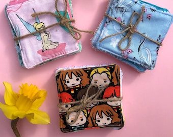 May include: A set of three reusable makeup remover pads. The pads are made of soft fabric and are decorated with different patterns. One pad features a cartoon image of Tinkerbell, another pad features a floral pattern, and the third pad features a pattern of cartoon characters from the Harry Potter series.