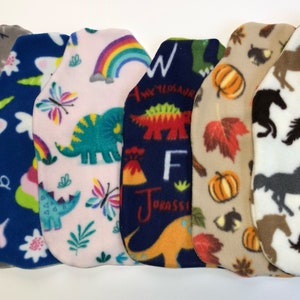 May include: Six different fleece fabric squares with various colorful patterns. The patterns include a snowman, a unicorn, dinosaurs, a rainbow, a pumpkin, and horses.