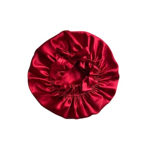 May include: A red satin sleep cap with a gathered ruffle around the edge and a tie at the back.