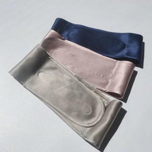 May include: Three satin headbands in different colors: gray, pink, and navy blue. Each headband has a padded section for comfort.