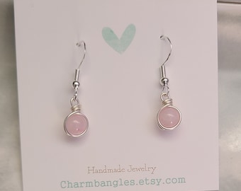 May include: A pair of silver dangle earrings with pink round gemstone beads. The earrings are displayed on a white card with the text "Handmade Jewelry Charmbangles.etsy.com".