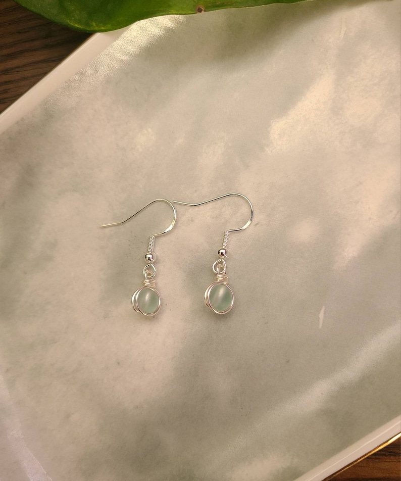 May include: A pair of silver dangle earrings with light blue round stones.