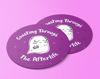 May include: Two purple round coasters with a white ghost illustration and the text "Coasting Through The Afterlife" and "HARVEST MOON GEMZ".