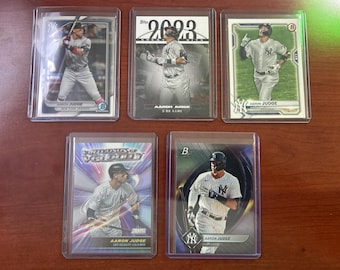 May include: Five baseball trading cards featuring Aaron Judge, a player for the New York Yankees. The cards are from different sets, including 2023 Topps, 2023 Topps 'The Game', and 2023 Topps 'Velocity'.