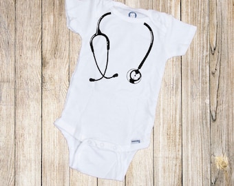 May include: White baby onesie with a black and white graphic of a stethoscope.
