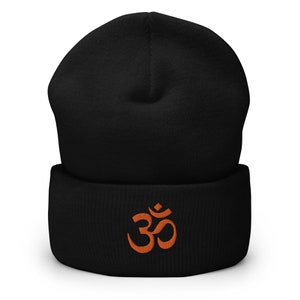 Puede incluir: Gorro negro con un símbolo Om naranja bordado en la parte delantera.