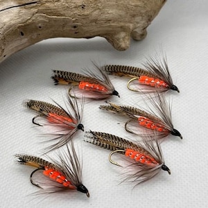 May include: Six brown and orange fly fishing lures with orange beads and feathers.