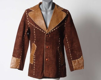 May include: A brown suede jacket with a tan leather collar and trim. The jacket has decorative stitching around the edges and pockets.