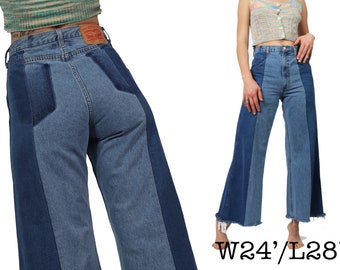 May include: Wide-leg jeans in blue denim with a patchwork design. The jeans have a high waist and a wide leg opening. The jeans are made from soft, comfortable denim and have a relaxed fit. The jeans are labelled with the size "W24/L28".