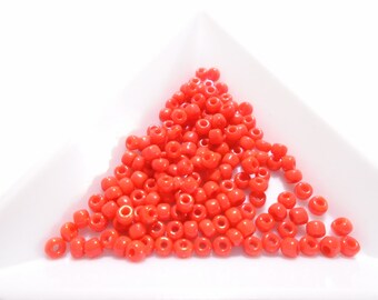 May include: A pile of small, bright orange glass beads. The beads are round and have a smooth, glossy finish.