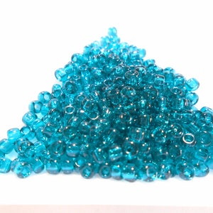 Puede incluir: Un montón grande de cuentas de semillas de vidrio azul turquesa. Las cuentas son pequeñas y redondas, y son perfectas para hacer joyas u otros proyectos de manualidades.