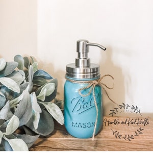 May include: A teal blue mason jar soap dispenser with a stainless steel pump and a brown twine bow. The jar is labeled "Ball Mason".