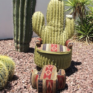 K&ouml;nnte beinhalten: Ein gr&uuml;ner Kaktus-f&ouml;rmiger Stuhl und Hocker mit einer s&uuml;dwestlichen gemusterten Stoffpolsterung. Stuhl und Hocker stehen auf einem Kiesbett.