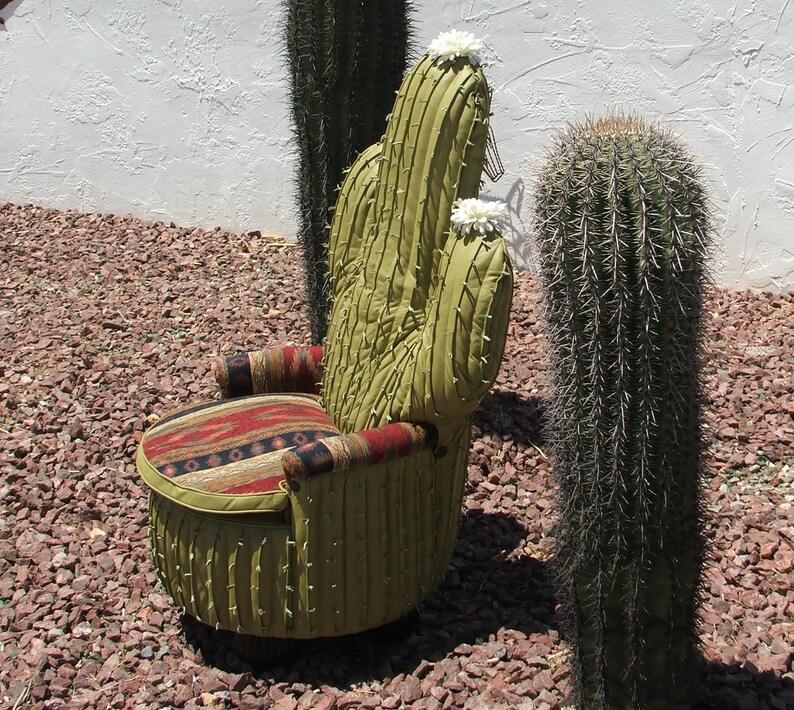 K&ouml;nnte beinhalten: Ein gr&uuml;ner Kaktus-f&ouml;rmiger Stuhl mit einem gemusterten Stoffkissen. Der Stuhl steht im Freien und ist von Kies umgeben.